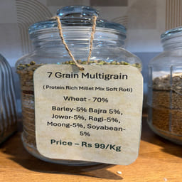 Glass jar labeled '7 Grain Multigrain' with a price tag on a wooden surface.